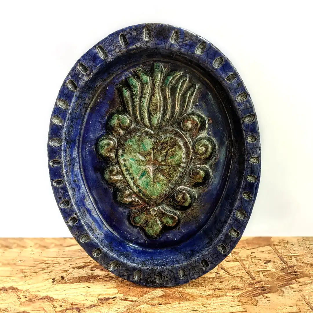 Plato ovalado de cerámica rakú esmaltado en azul profundo con un corazón milagroso en alto relieve decorado con tonos verdes.